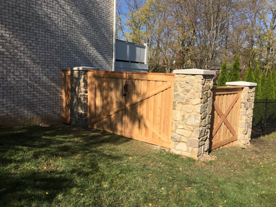 Custom wood privacy fence with double gate attached to stone pillars